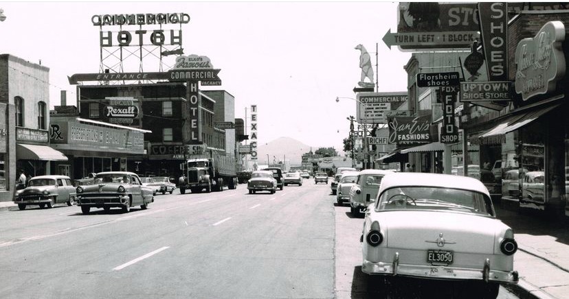 Vintage street scene featuring classic cars and historic storefronts