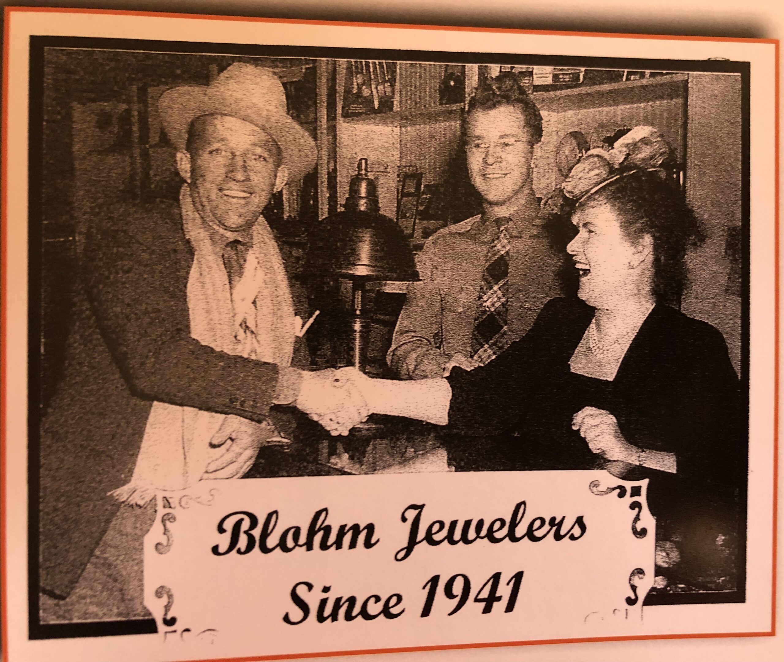 Three people shake hands at a jewelry store, celebrating Blohm Jewelers' long-standing history since 1941